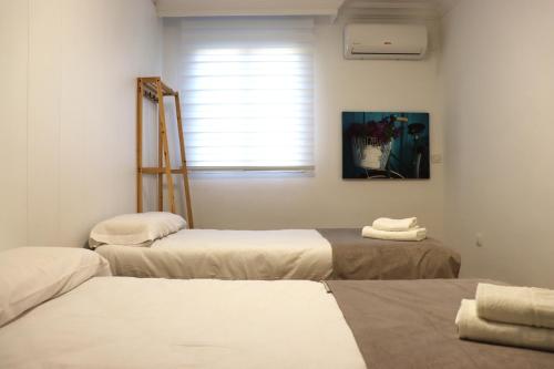 3 camas en una habitación con ventana en NightInSevilla Juglar Free parking, en Sevilla