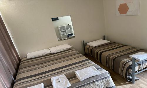 um pequeno quarto com 2 camas e um espelho em St George Hotel Motel em Saint George