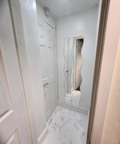 a white hallway with a mirror and a marble floor at Flat in Solihull town centre, 2 Big rooms in Solihull