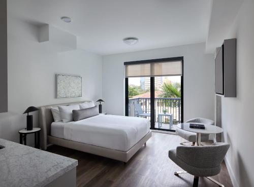 a white bedroom with a bed and a balcony at AKA West Palm in West Palm Beach