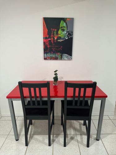 a red dining room table with two chairs and a painting at Cozy Spacious Guest Suite in Englewood