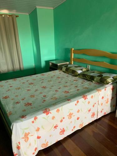 a bedroom with a bed with a floral bedspread at Apto de 6a8 Pessoas a 50m Praia aceita Pets in Cidreira