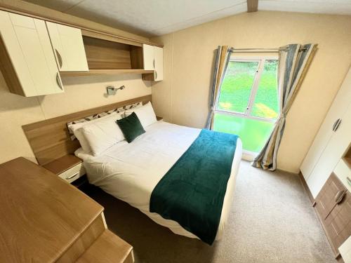 a small bedroom with a bed and a window at Luxury 2 Bedroom Caravan LG13, Shanklin, Isle of Wight in Shanklin
