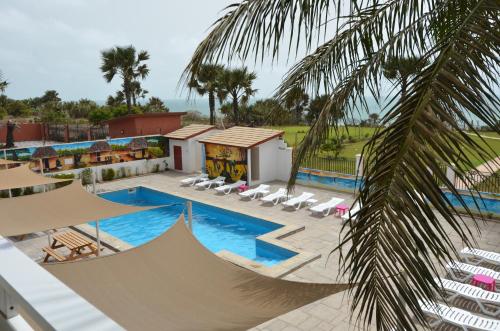 un complexe avec une piscine, des chaises et un palmier dans l'établissement Ocean Villa Heights, à Brufut