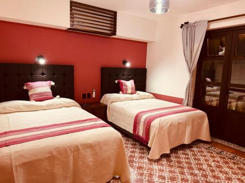 2 łóżka w pokoju z czerwonymi ścianami w obiekcie Lidia Anturios w mieście Oaxaca