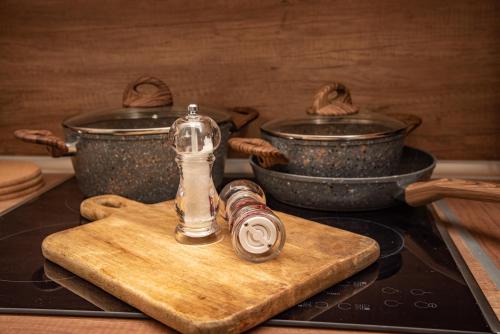 a bottle on a cutting board on a stove with two pots at Serenity by Elite Dwellings in Portariá