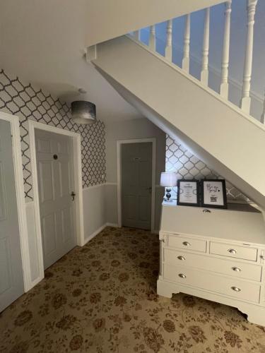 a room with a white dresser and a staircase at Fair Green B&B in Ballygawley