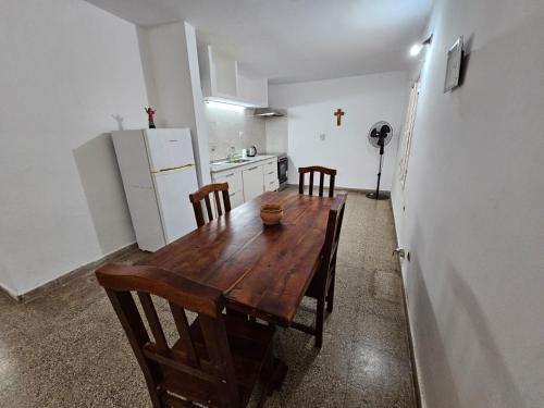 cocina con mesa de madera con sillas y nevera en Departamento zona norte en La Rioja