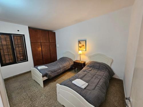 1 dormitorio con 2 camas, silla y lámpara en Departamento zona norte en La Rioja