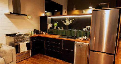 a kitchen with a stainless steel refrigerator and a stove at Te Aka Treehouse in Nelson Creek
