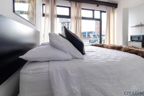 a bedroom with a white bed with pillows and a window at Hotel Citadin Zona 4 in Guatemala