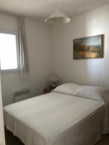 - un lit blanc dans une chambre avec fenêtre dans l'établissement Direct sea access, patio, lawn, private parking Reservations Saturday to Saturday only, à Saintes-Maries-de-la-Mer