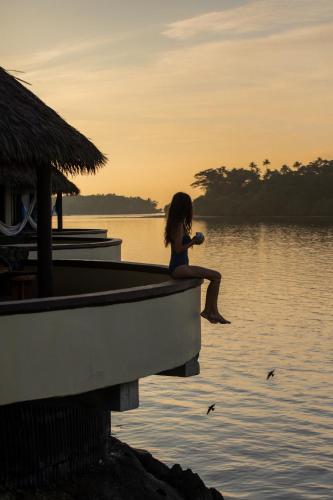 a girl sitting on the edge of a boat in the water at Koro Sun Resort & Rainforest Spa in Savusavu