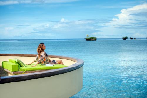 a woman sitting on a green chair in the ocean at Koro Sun Resort & Rainforest Spa in Savusavu