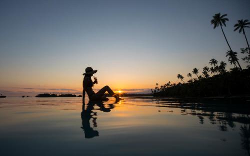 a person sitting on the beach watching the sunset at Koro Sun Resort & Rainforest Spa in Savusavu