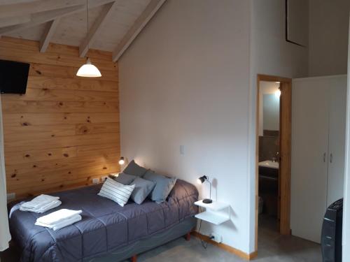 a bedroom with a bed with a wooden wall at Las Casitas 1 in San Martín de los Andes