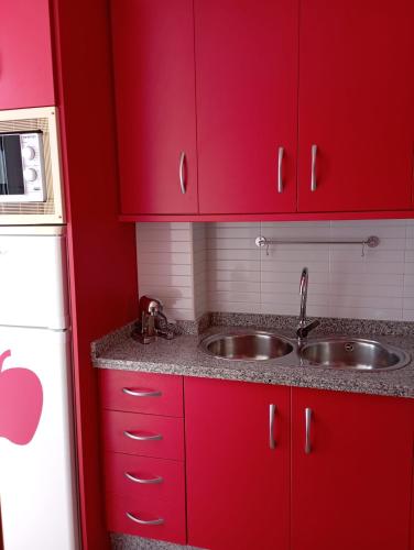 uma cozinha com armários vermelhos e um lavatório em Apartamento Duquesa em Rute
