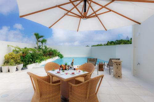 a patio with a table and chairs and an umbrella at ResortVilla-KAPUKA in Kouri