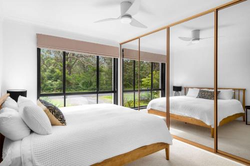 a bedroom with two beds and large windows at Villa Del Mar - Belle Escapes Jervis Bay in Vincentia