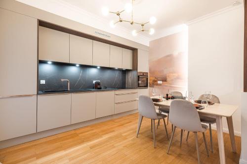 une cuisine avec des armoires blanches et une table et des chaises dans l'établissement Apartment - Le Bloom In the heart of Annecy, à Annecy