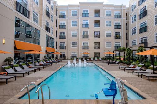 a pool in front of a building with chairs and umbrellas at Luxury Executive 2 Bedroom/2 Bathroom Boutique Apt in Charlotte