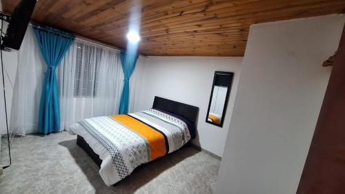 1 dormitorio con 1 cama con cortinas azules en Habita Living Bogotá, en Bogotá