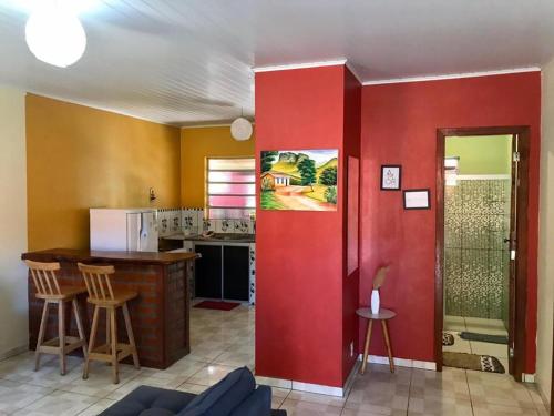 a living room with a red wall and a kitchen at Casa Rosa in Vale do Capao