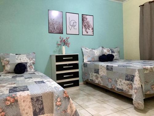 a bedroom with two beds and a dresser at Casa Rosa in Vale do Capao