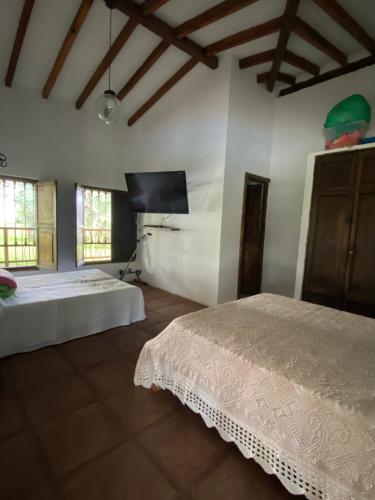 a bedroom with two beds and a flat screen tv at Finca ganadera de lujo en el Quindío in Pueblo Tapao