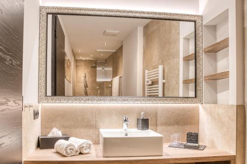 een badkamer met een wastafel en een spiegel bij Exklusiv und elegantes Apartment in der Residenz Silvretta inkl Silvretta Premium Summer Card in See