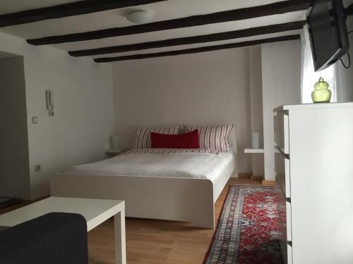 sypialnia z białym łóżkiem i czerwoną poduszką w obiekcie Baumeisterhaus Apartment w mieście Bad Hersfeld