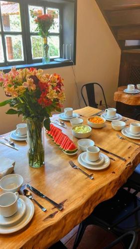 a wooden table with a vase of flowers on it at Pousada Motta in Miguel Pereira