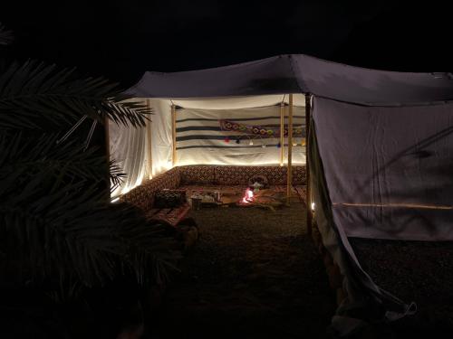 a bed in a tent at night with a fire at Mountain house in Al-ʿUla