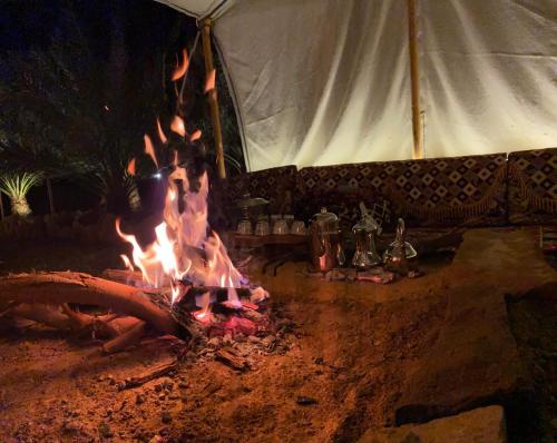 a fire pit in front of a tent at night at Mountain house in AlUla