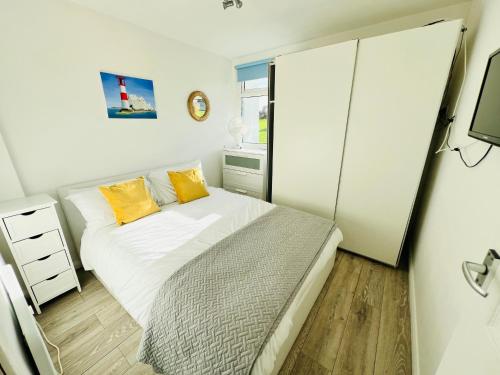 2 Bedroom Chalet SB22, Sandown Bay, Isle of Wight, Dog Friendly في سانداون: غرفة نوم صغيرة مع سرير مع وسائد صفراء