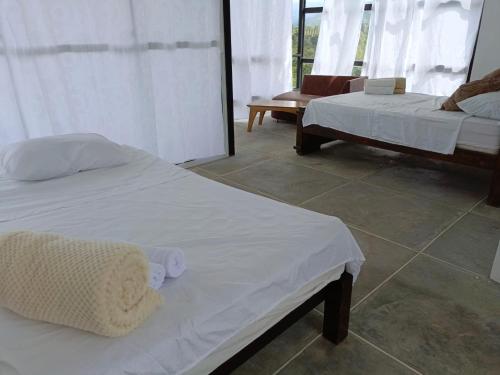 two beds in a room with white sheets at Finca Maratón Alto in Calarcá
