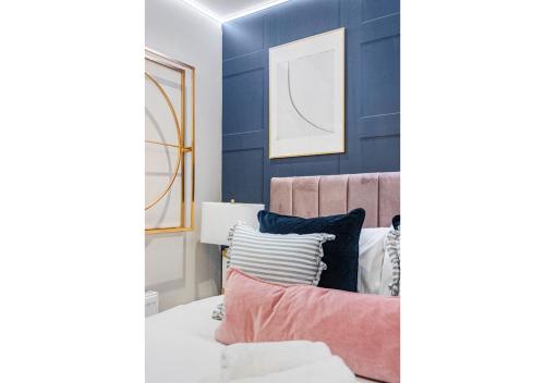 a bedroom with blue walls and a bed with pillows at Modern London 3-Bedroom Flat in London