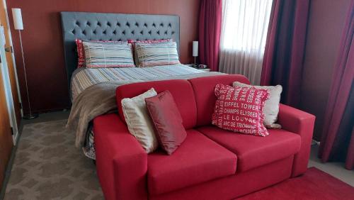 un sofá rojo con almohadas junto a una cama en Happy Home with 8 bedrooms en Taupo
