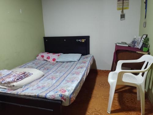 um pequeno quarto com uma cama e uma cadeira em Alojamiento Don Luis em Popayan