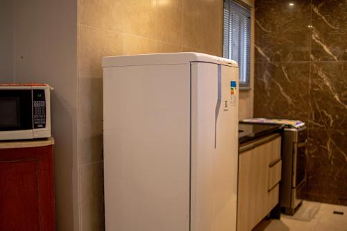 a white refrigerator in a kitchen next to a microwave at Ipanema Vinicius de Moraes II in Rio de Janeiro