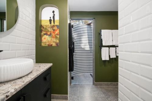 a bathroom with green walls and a sink and a mirror at Tamborine Mountain Glades in Mount Tamborine