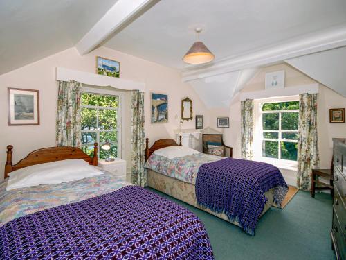 a bedroom with two beds and two windows at Carreg Yr Eos - Cottage in Fishguard