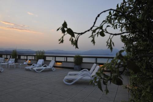 a group of white chairs sitting on a patio at Hotel Acquaviva Del Garda in Desenzano del Garda