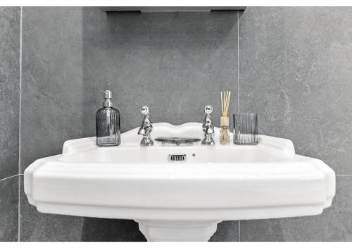a white sink with two figurines on it in a bathroom at Tranquility in Bloom: Refreshing 2BR Apartment in London
