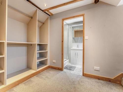 a walk in closet with white walls and wooden shelves at Rod Line Cottage in Croft