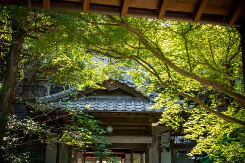 a house with a blue roof and trees at Kagetsu Taisyokan in Takeo