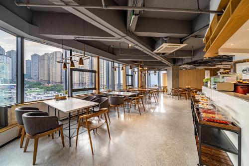 a restaurant with tables and chairs and windows at Wuyu Hotel - Chongqing Yuanyang Light Rail Station in Chongqing
