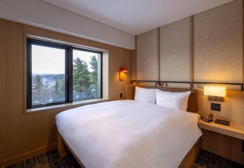 富良野Nozo Hotel的带窗户的房间里有一张白色的大床