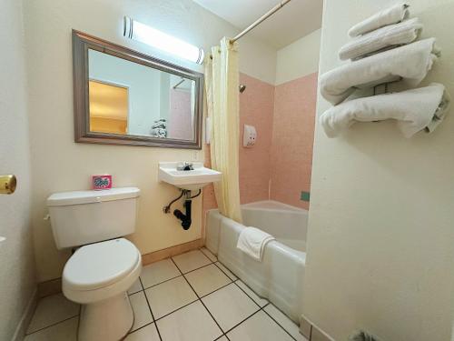 a bathroom with a toilet and a sink and a tub at Royal Inn and Suites in Hemet