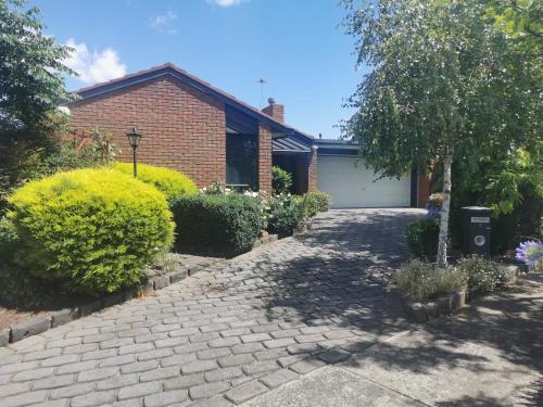 a brick house with a driveway and a garage at Peaceful House In Mill Park Melbourne in Mill Park